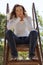 Young woman sitting top of ladder jeans white top