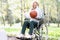 Young woman sitting in wheelchair holding basketball in park