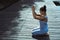 A young woman is sitting on a wooden pier with her hands folded in a prayer position on her head. General side view. Meditation,