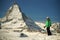 Young woman skier standing on snow on backgroung of Matterhorn mountain and bright blue sky, freeride skiing in the Alps