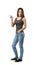 Young woman in sleeveless top and jeans standing in half-turn with left hand in pocket and right hand pointing sideward