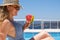 Young woman with slice of watermelon in straw hat sunbathing sitting on the edge of swimming pool