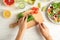 Young woman slices cucumber for salad on wooden background