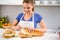 Young woman slicing loaf of bread in kitchen