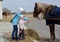 A young woman with a small daughter feeds the horse hay outdoors. Kaliningrad region