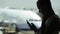 Young woman with smart phone at the airport with airplane on the background