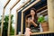 Young woman with smartphone outdoors, weekend away in container house in countryside.