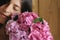 Young woman smelling beautiful hydrangea bouquet on background of  rustic wood. Stylish girl holding pink and purple hydrangea