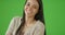A young woman smiles at the camera on green screen