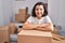 Young woman smiling confident leaning on cardboard box at new home