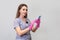 Young woman smiling cosmetologist in rubber gloves holds smartphone on gray background. Online booking cosmetology