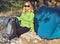 Young Woman with Smiling Face Hiker sitting with backpack and Tent Camping Outdoor