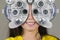 Young woman smiling happy looking through optometric hospital device and checking eyes having sight exam in ophthalmology health