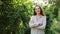 Young woman smiling outdoor. Beautiful brunete girl resting on park or garden green background. Free happy woman at