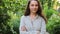 Young woman smiling outdoor. Beautiful brunete girl resting on park or garden green background. Free happy woman at