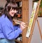 Young woman smiling painting on canvas with oil paints at home