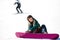Young woman snowboarder zips up his boots sitting on a snowy slope