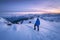 Young woman in snowy mountains at sunset in winter