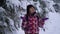 Young woman in the snowy woods. Young pretty tourist stands alone in the forest and looks around. She catches snowflakes