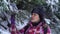 Young woman in the snowy woods. Young pretty tourist stands alone in the forest and looks around. She looks at snow and