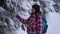 Young woman in the snowy woods. Young pretty tourist stands alone in the forest and looks around. She looks at snow and