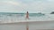 Young woman spending summer at seaside. Cheerful girl running along beach.