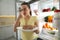 Young woman with spoiled sausage near refrigerator in kitchen