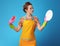 Young woman with sponge looking at washed dish on blue