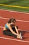 Young Woman in Sports Bra Stretching Hamstring on Track