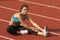 Young Woman in Sports Bra Stretching Leg Muscles on Track