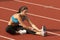 Young Woman in Sports Bra Stretching Leg on Track