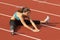 Young Woman in Sports Bra Stretching Legs on Track