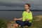 Young woman in sportswear sitting on river shore