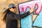 Young woman spraying paint on a graffiti wall