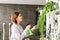 Young woman spraying plants at home