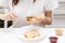 A young woman spreads peanut butter paste on bread, prepares an American sandwich