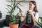 Young woman sprinkles water on indoor houseplant. Housewife busy with housework enjoy process takes care of domestic lush home