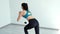 Young woman squats with gliding discs in white light fitness club in slow motion