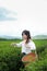 Young woman stand in the tea plantation surrounded by sky and mountain view. Singha Park Tea Plantation at Chiangrai, Thailand