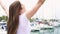 Young woman standing alone on pier. Inspired carefree female raising her arms up in slow motion