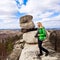 Young woman standing with camera on cliff`s edge.