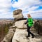 Young woman standing with camera on cliff`s edge.