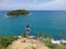 Young woman standing on a cliff with seaview to a island, on Phuket island Rawai viewpoint