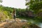 Young woman standing on edge of rock and stretching, practicing yoga. view of quarry with water.