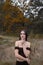 A young woman is standing in a forest, enjoying carefree autumn day in the nature