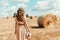 Young woman standing on harvested field with straw bales. Agriculture background with copy space. Summer and autumn harvest