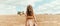 Young woman standing on harvested field with straw bales. Agriculture background with copy space. Summer and autumn harvest