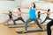 Young woman standing in lunging asana Virabhadrasana in yoga studio