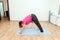 Young woman standing on mat in one of yoga positions