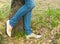 Young woman standing near a tree, legs, jeans, shoes closeup